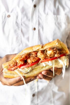 Close up photo of hands holding a New Orleans Shrimp Po' Boy