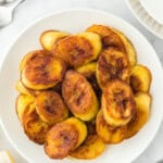 A white plate against a white background with slices of fried sweet plantains