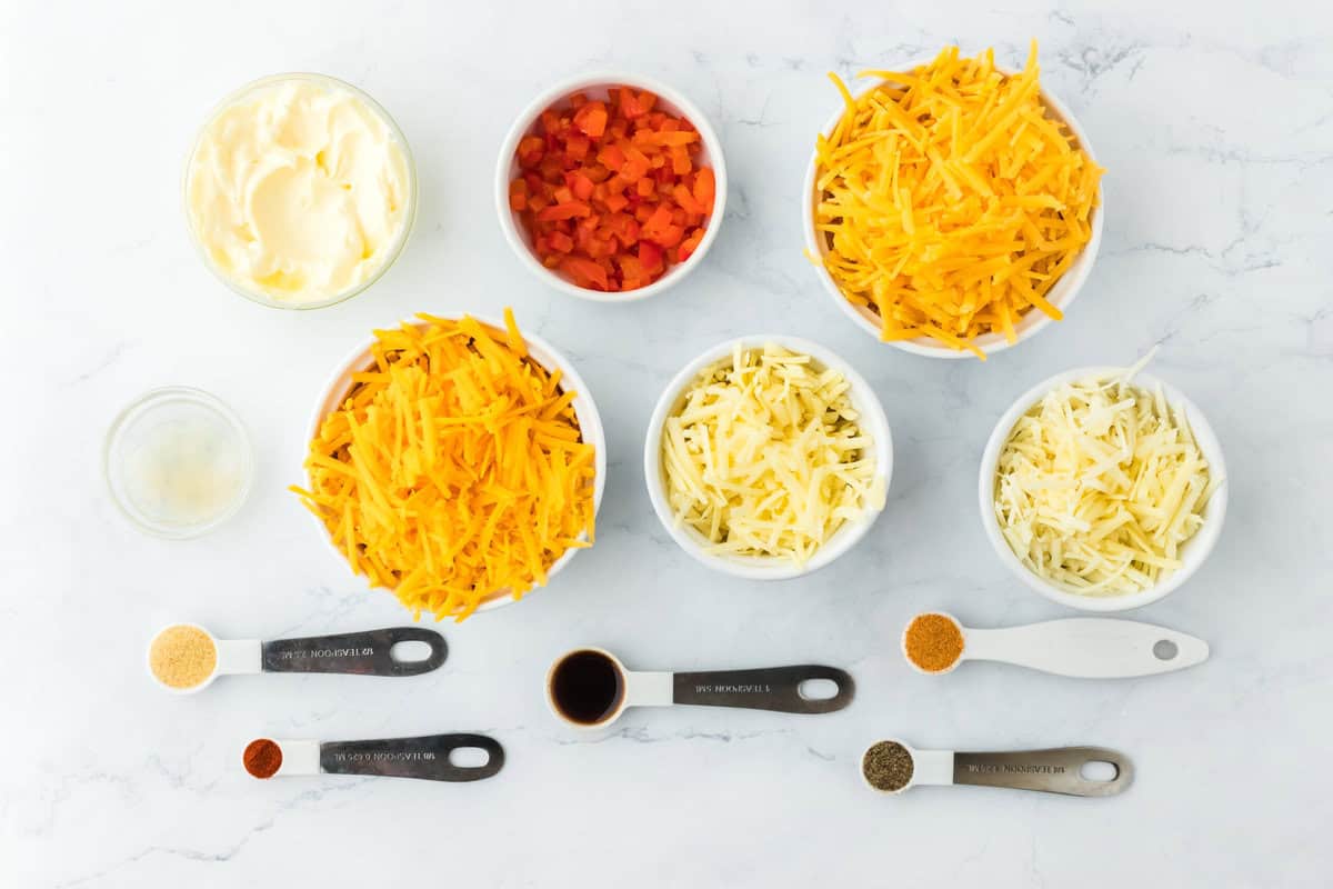 Ingredients in white bowls and measuring spoons to make a homemade pimento cheese