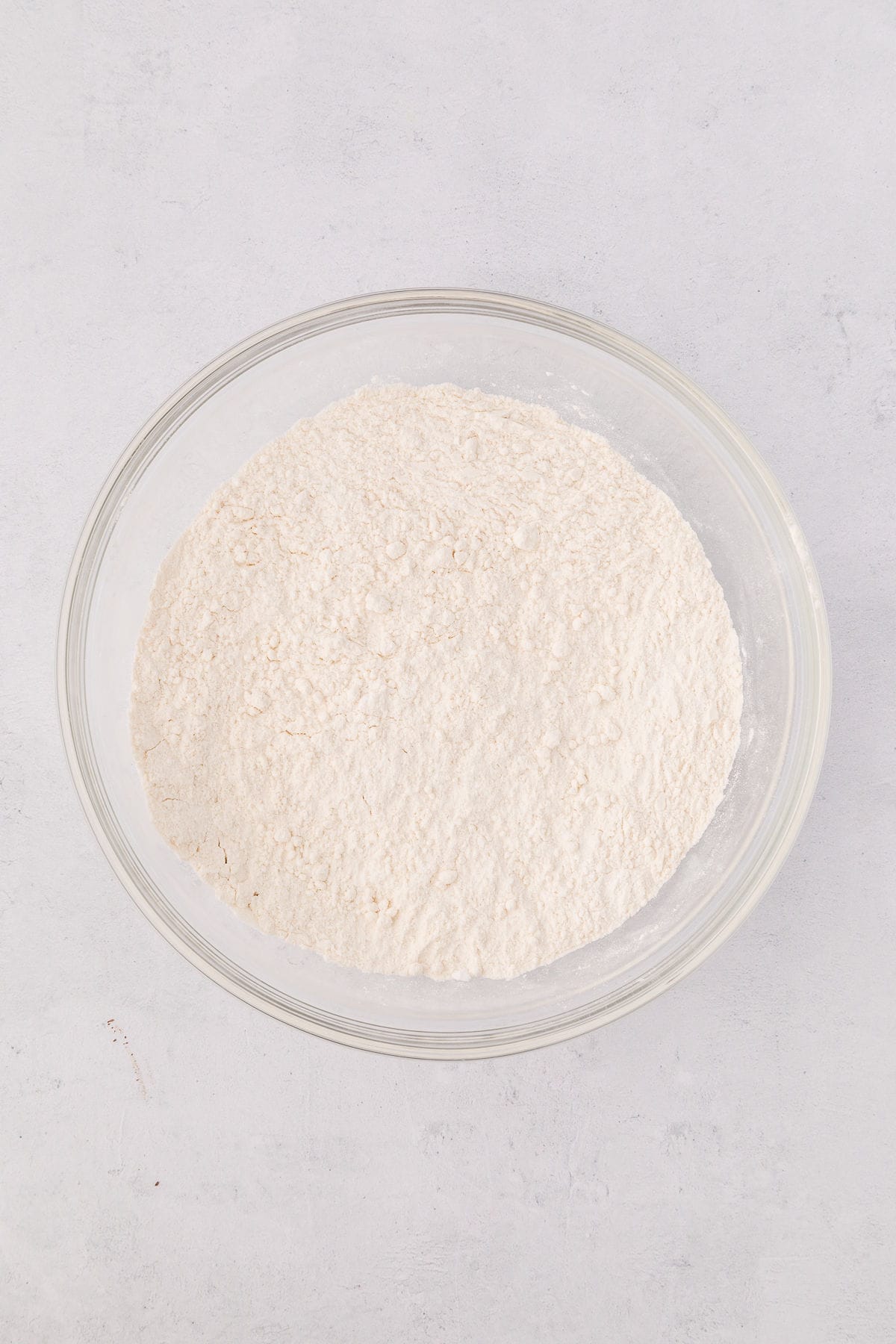 Dry ingredients mixed together in a glass bowl on white countertop