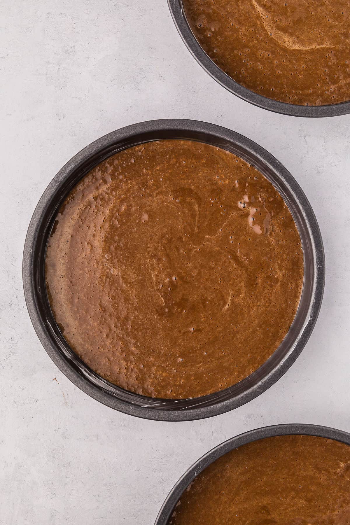 Chocolate batter in three cake pans before baking.