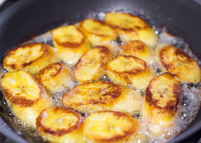 Plantains turning golden brown in butter as they fry