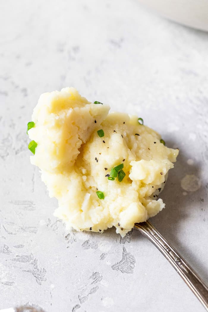After learning how to make garlic mashed potatoes, a spoon of potatoes is in center of photo 