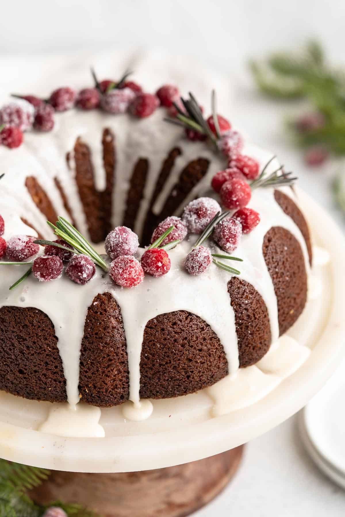 A close up of the best Gingerbread cake with white glaze on white cake stand.