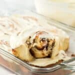 A side view of a homemade cinnamon roll with a bite taken out, highlighting the swirled cinnamon filling