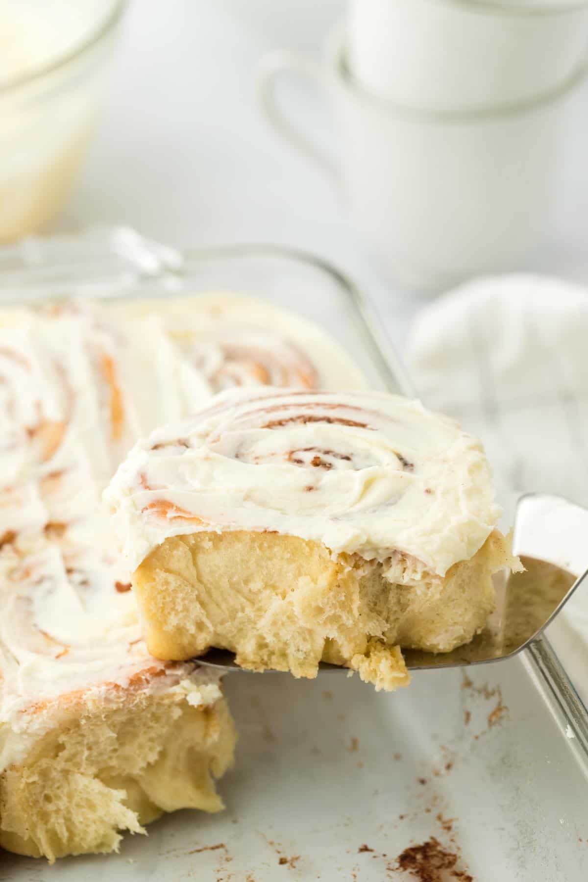 A spatula holding a homemade cinnamon roll, showcasing its fluffy texture and swirled filling