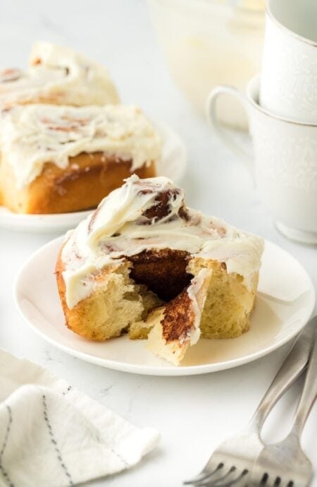 A homemade cinnamon roll on a white plate ready to serve