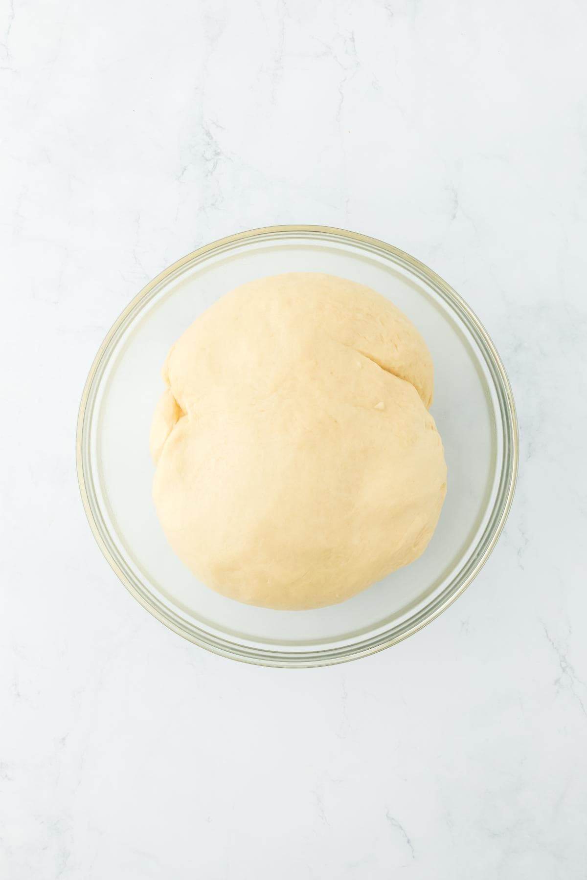 A glass bowl with fully risen dough