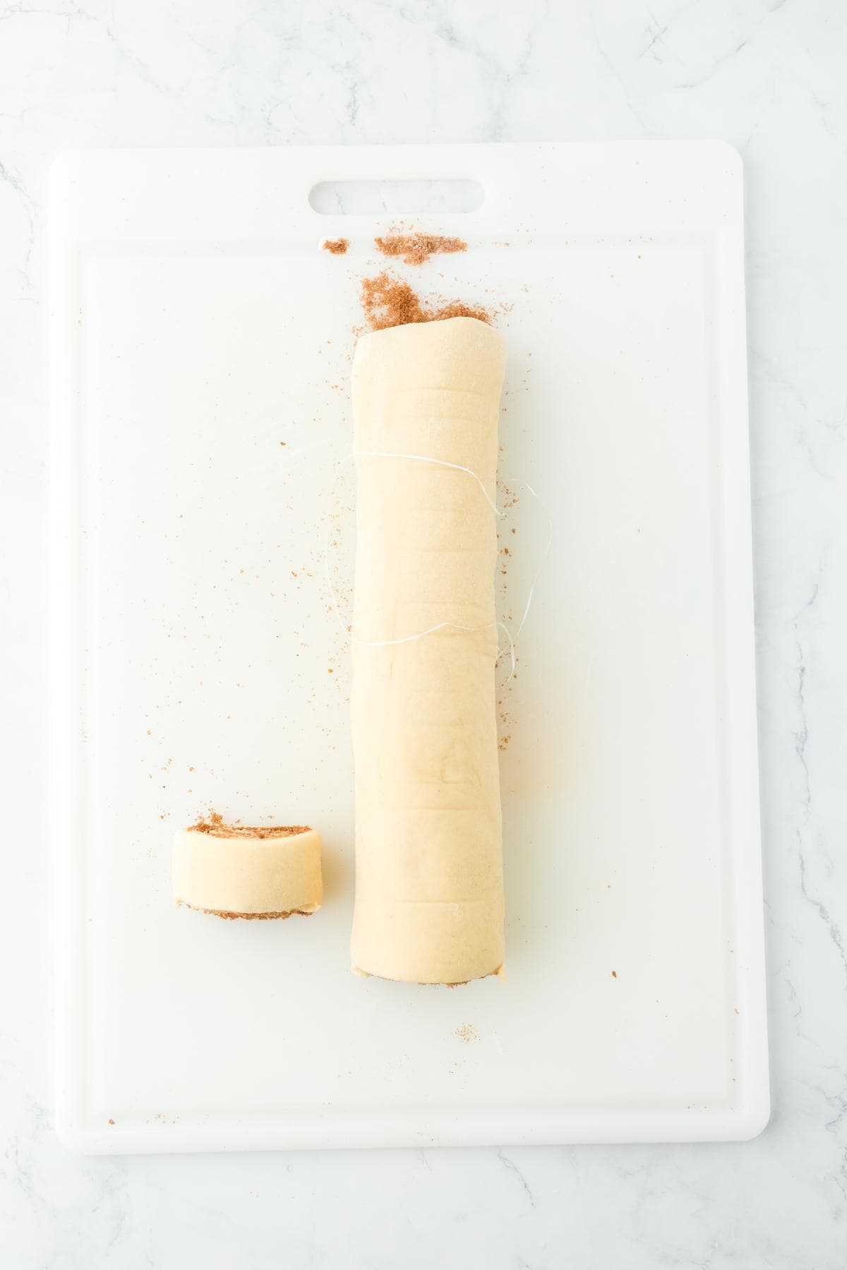 Dough rolled into a log with unflavored dental floss for cutting