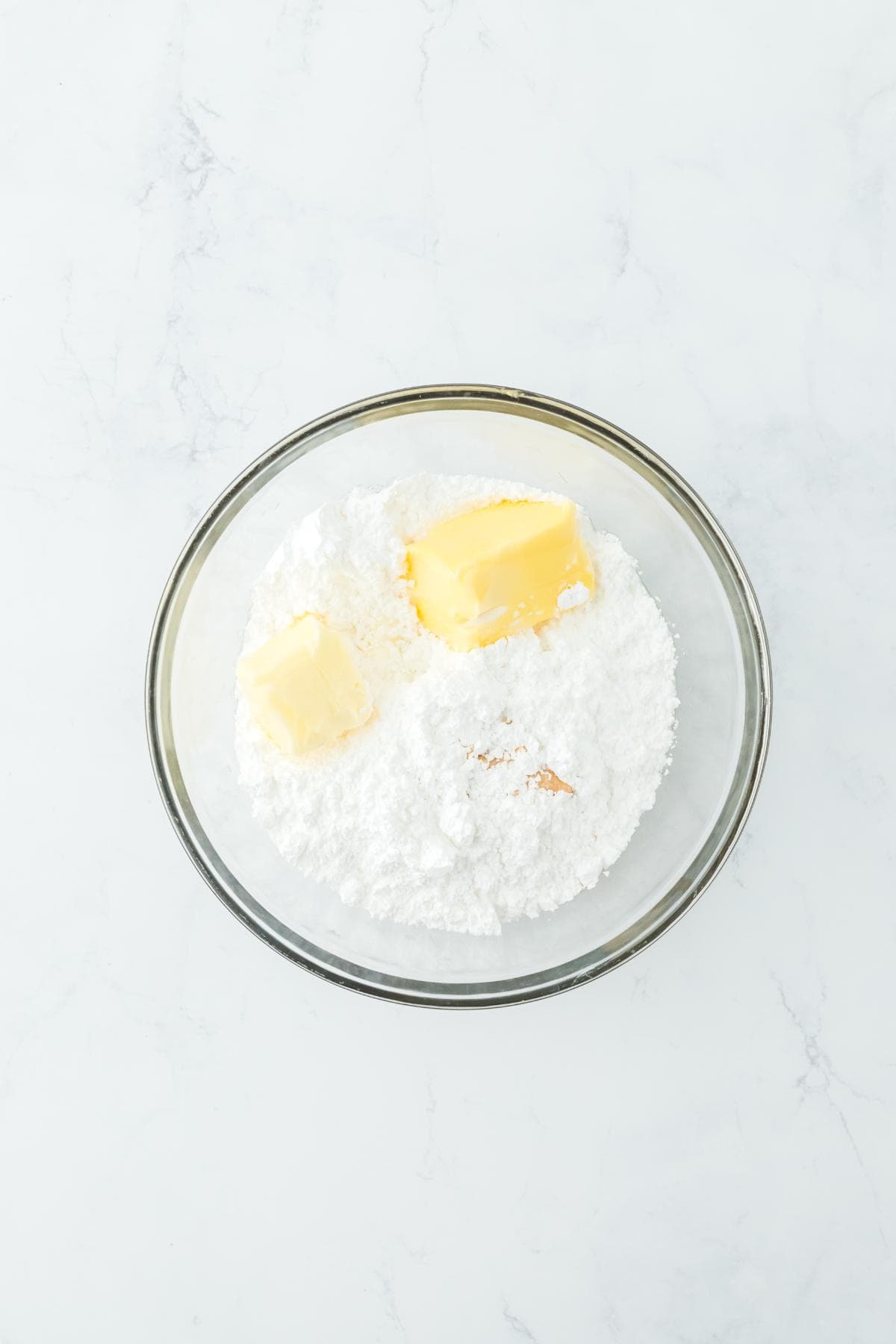 Ingredients for frosting, including butter and powdered sugar, in a bowl