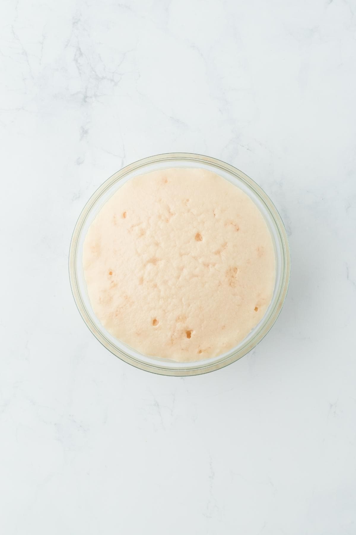 A glass bowl with bubbly, frothy proofed yeast