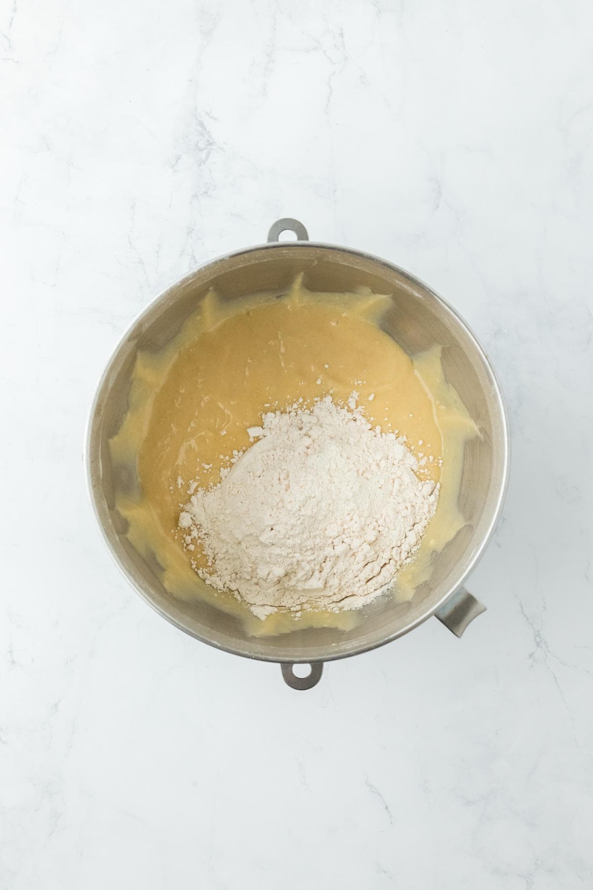 A mixing bowl showing dough partially combined with flour