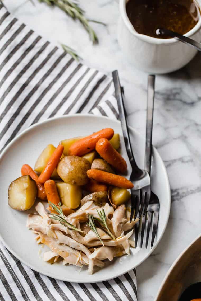A white plate with skinless shredded chicken with potatoes and carrots