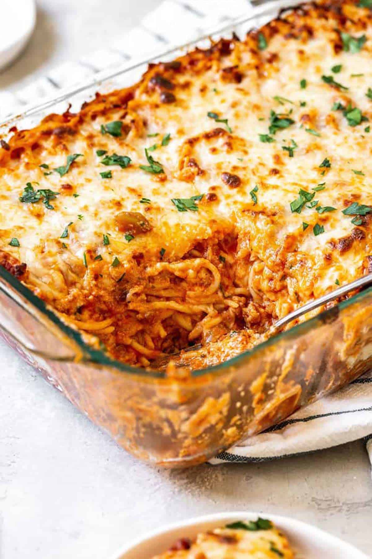 Baked spaghetti with cream cheese dug into and added to a plate
