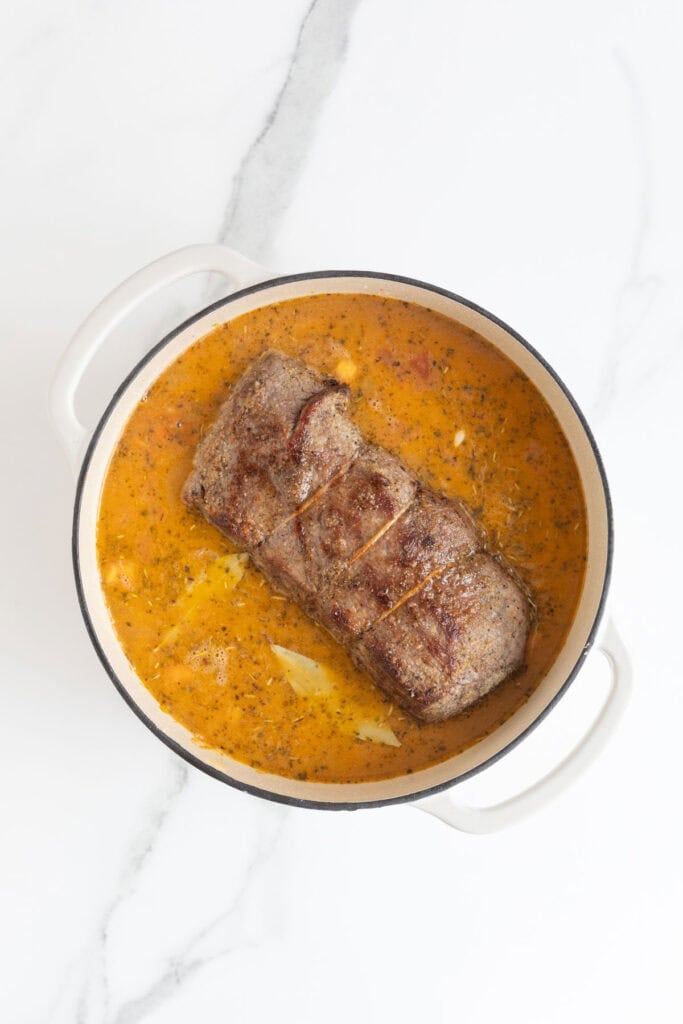 Roast added to a dutch oven with sauces simmering
