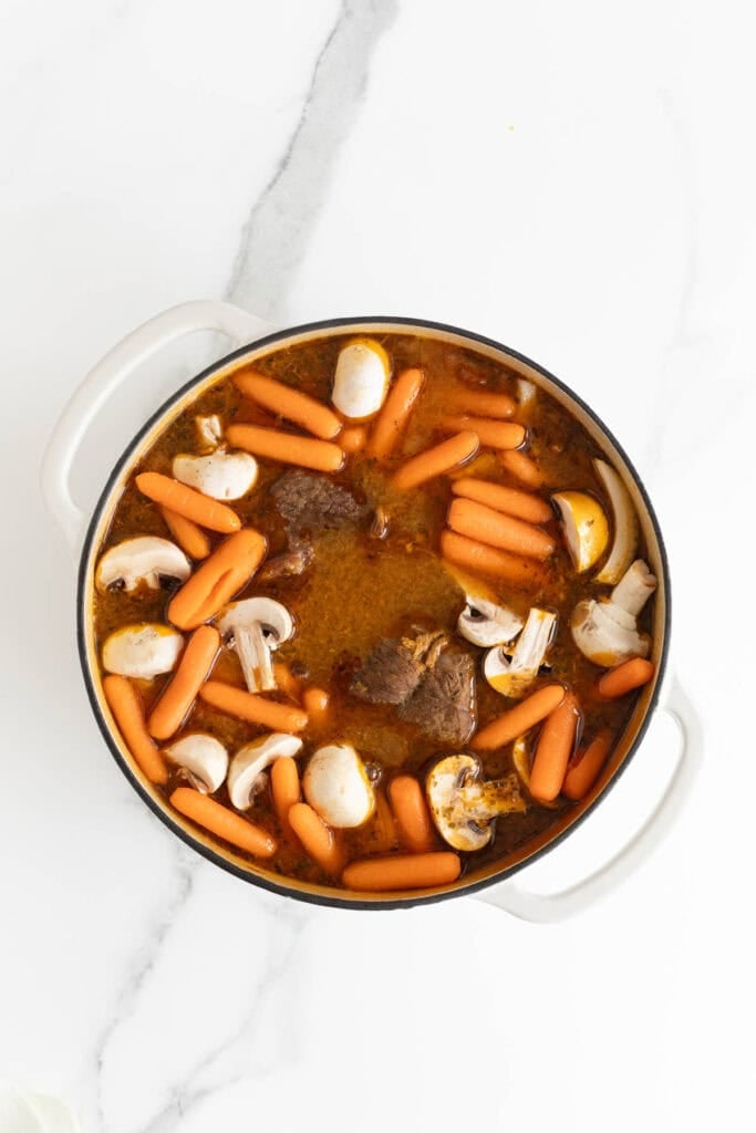 Carrots, potatoes and mushrooms in a dutch oven with a pot roast