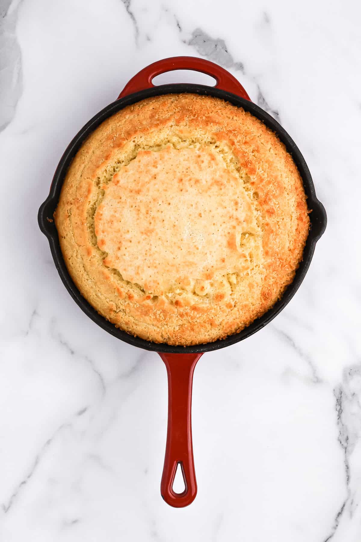 Golden cornbread in a cast iron skillet on white countertop