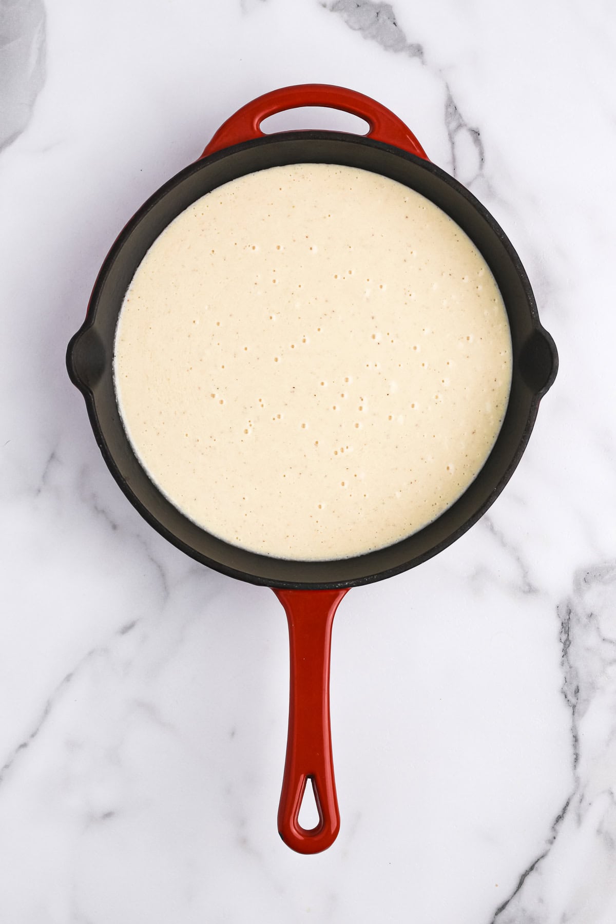 Cornbread batter in a greased cast iron skillet on white background