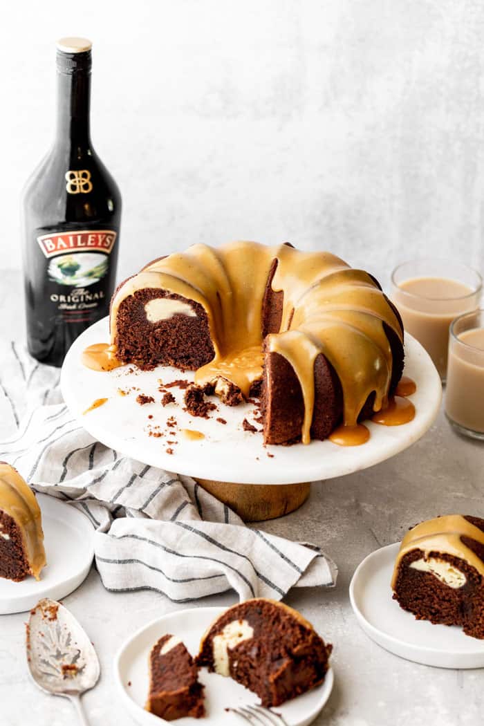 Sliced Baileys Chocolate Bundt Cake recipe with cream cheese filling on cake stand with slices around