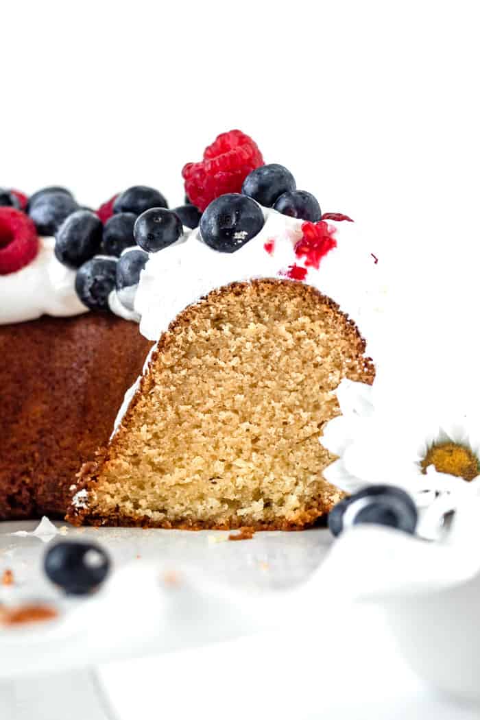 Close up of sliced old fashioned pound cake with whipped cream and berries ready to serve