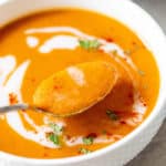 A spoon of creamy carrot ginger soup ready to serve