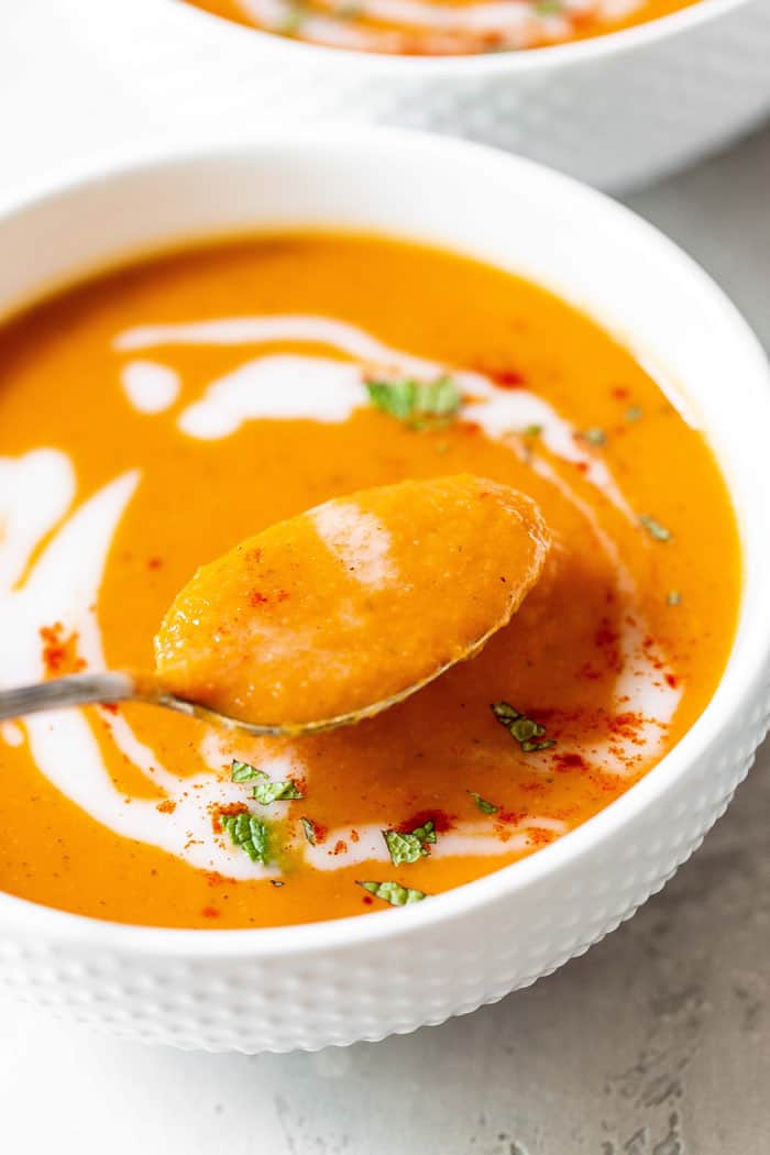 A spoon of creamy carrot ginger soup ready to serve