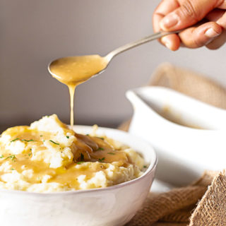 After learning how to make gravy from scratch, the homemade gravy is ladled over mashed potatoes