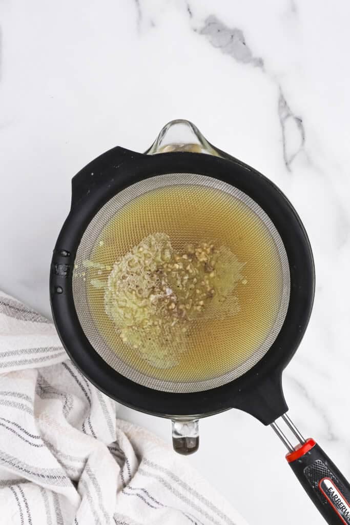 Chicken stock being strained into a bowl