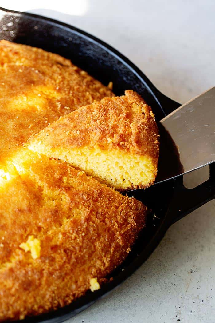 A slice of Southern cornbread recipe being taken out of a cast iron skillet