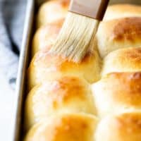 A close up of sweet rolls being brushed with melted butter