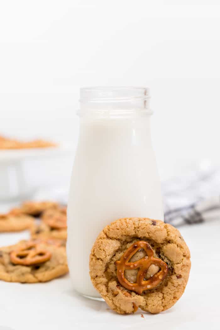 A homemade chocolate chip cookie next to glass of milk