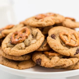 A white cake plate of homemade chocolate chip cookies with pretzels ready to serve
