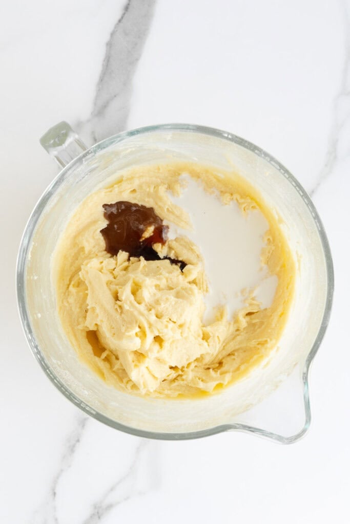 Vanilla and heavy cream added to stand mixer bowl to make a cake batter