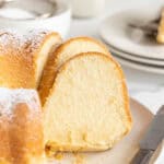 Slices of butter pound cake against a full cake on white plate with a knife