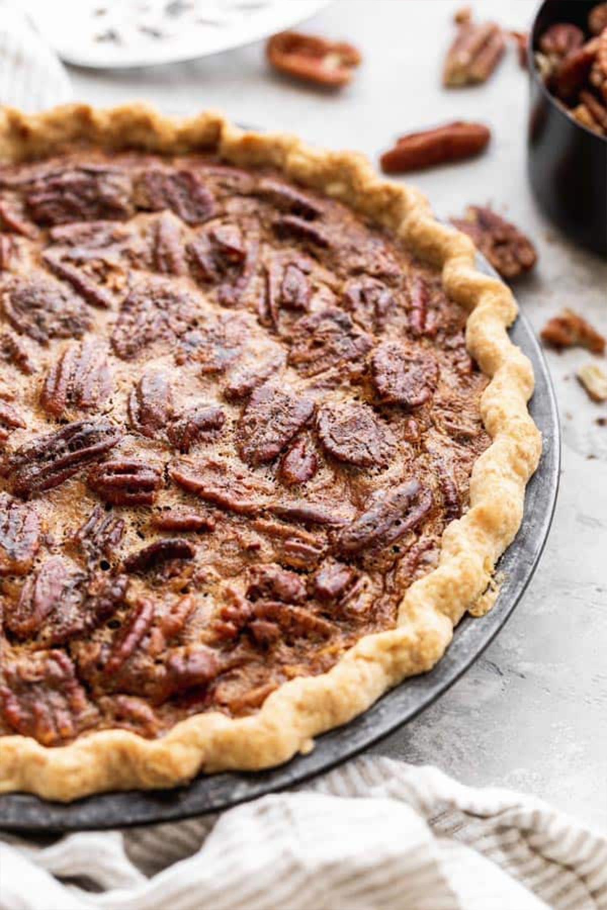 A close up pecan pie recipe with homemade crust with pecans surrounding it
