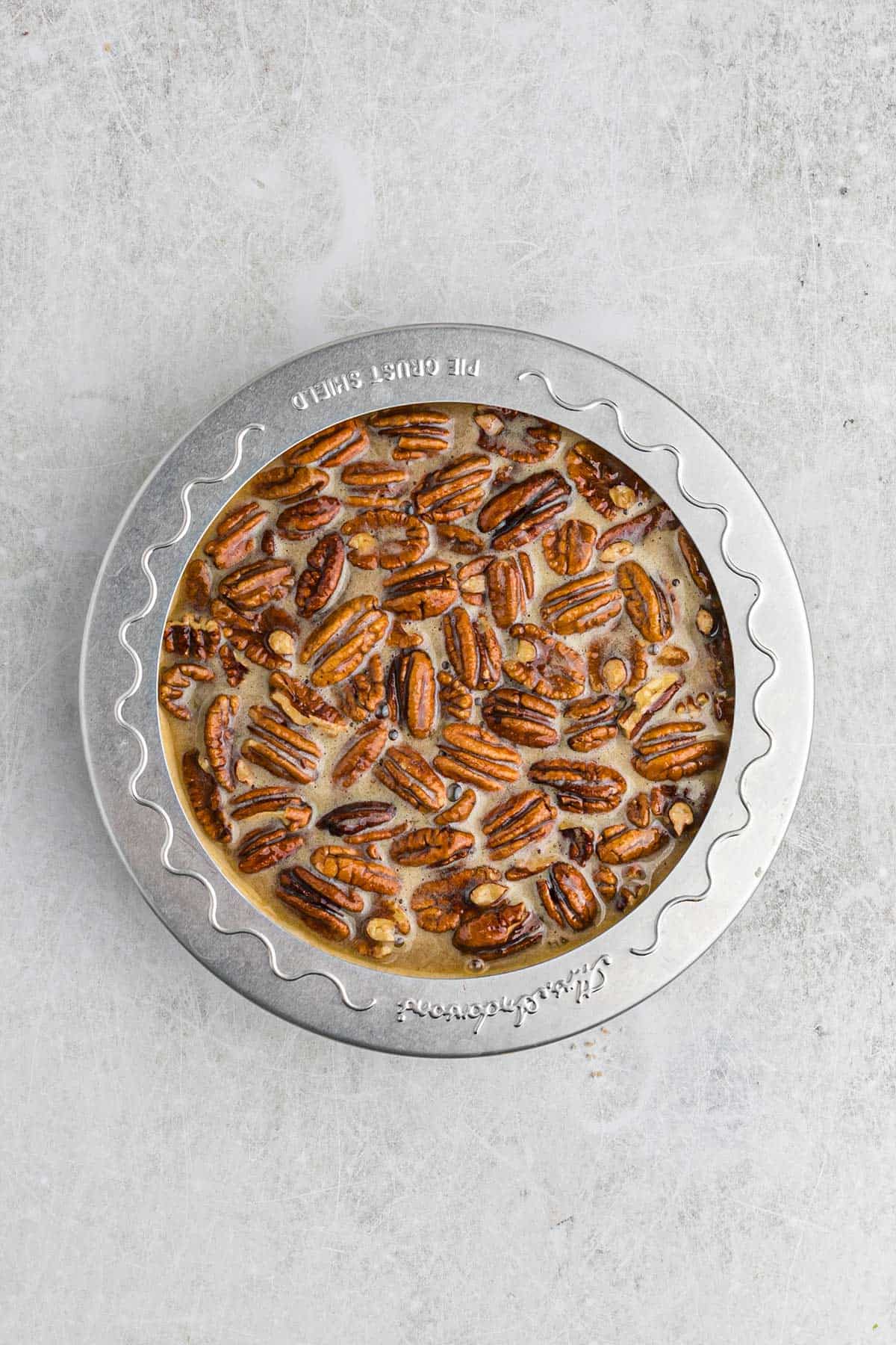 Adding a pie shield to protect the crust from burning.