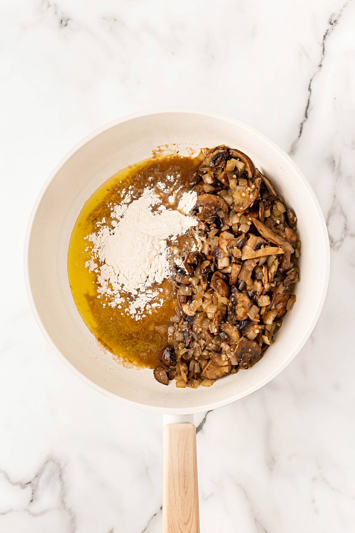Flour added to mushroom and onion mixture in a skillet to start the gravy