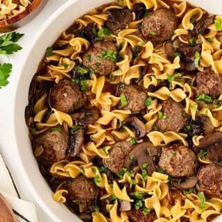 Closeup of Salisbury steak meatballs and egg noodles coated in rich mushroom gravy