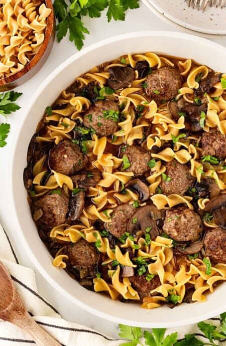Closeup of Salisbury steak meatballs and egg noodles coated in rich mushroom gravy