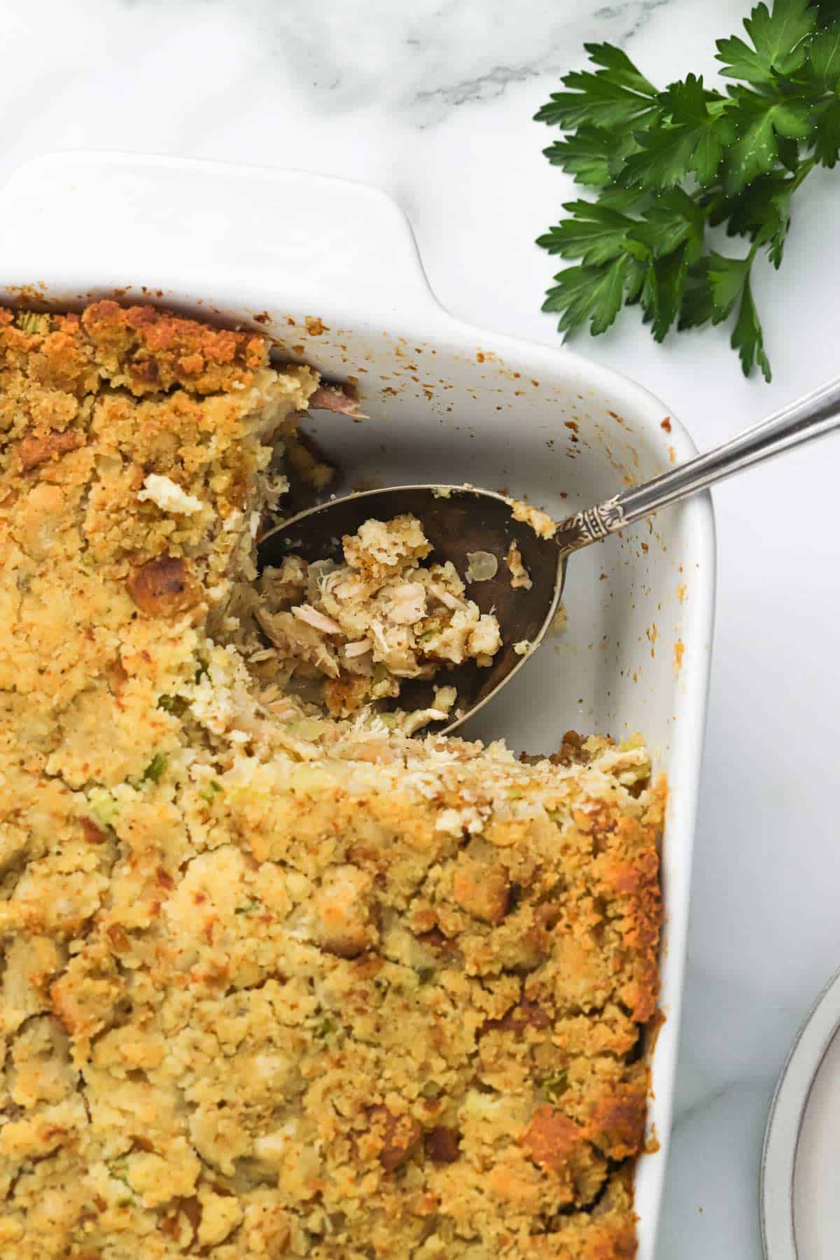 A casserole of southern cornbread stuffing with a scoop missing.