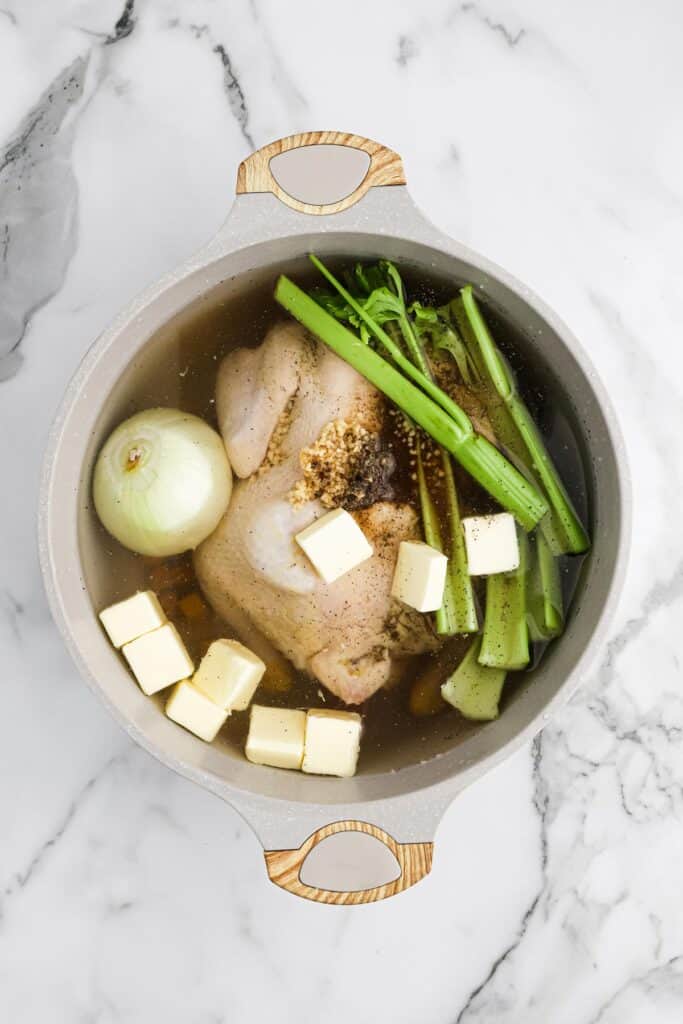 Ingredients in a pot to make homemade chicken stock for Southern dressing on white countertop