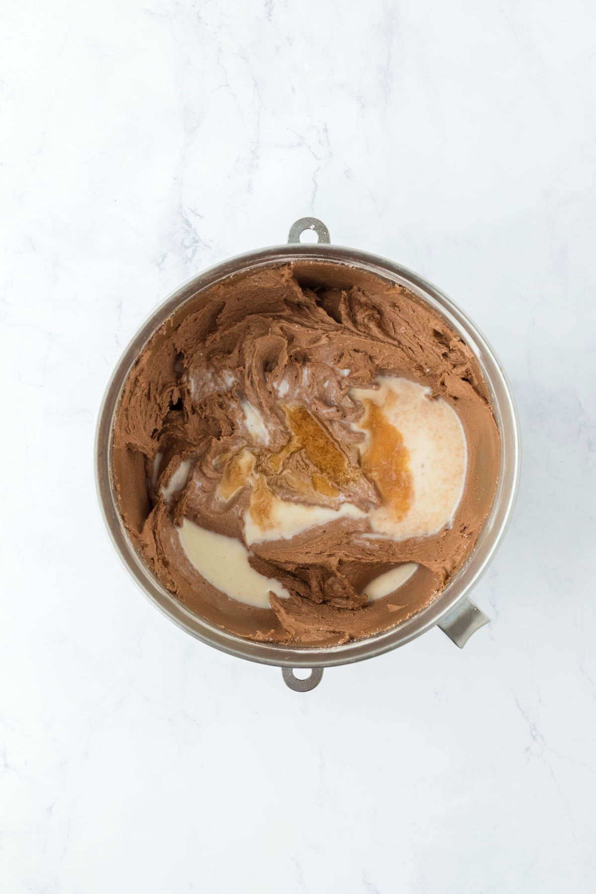 Buttermilk and vanilla added to chocolate cake batter on white countertop.