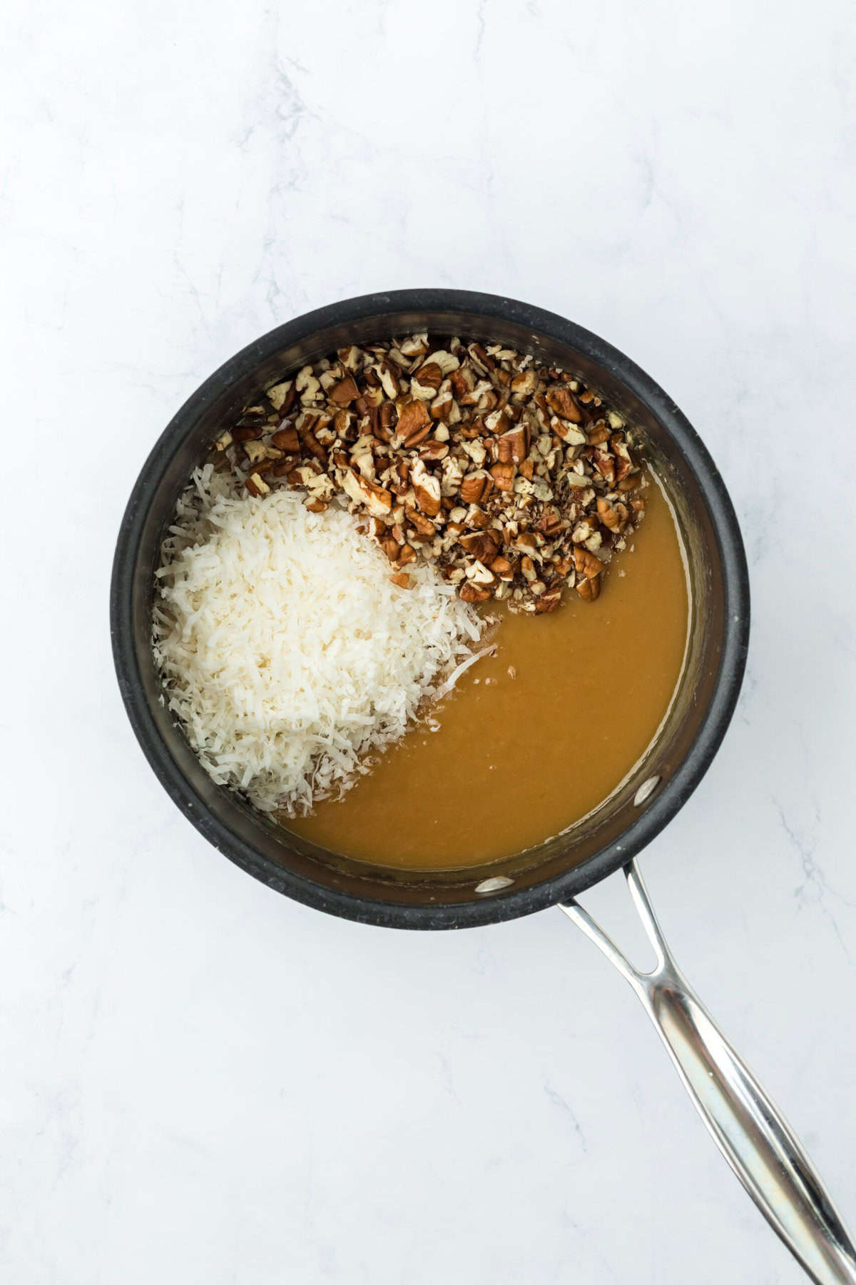 Coconut and pecans added to German chocolate cake icing in a pot