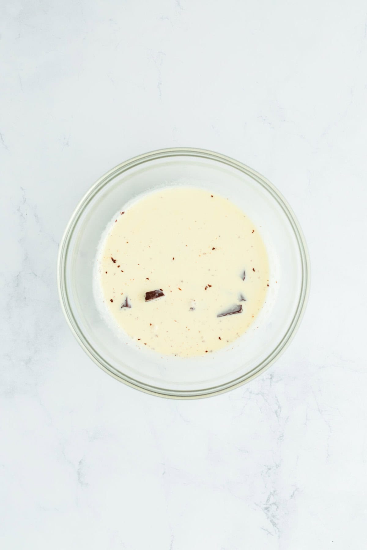 Heavy cream and chocolate in a glass bowl on white countertop