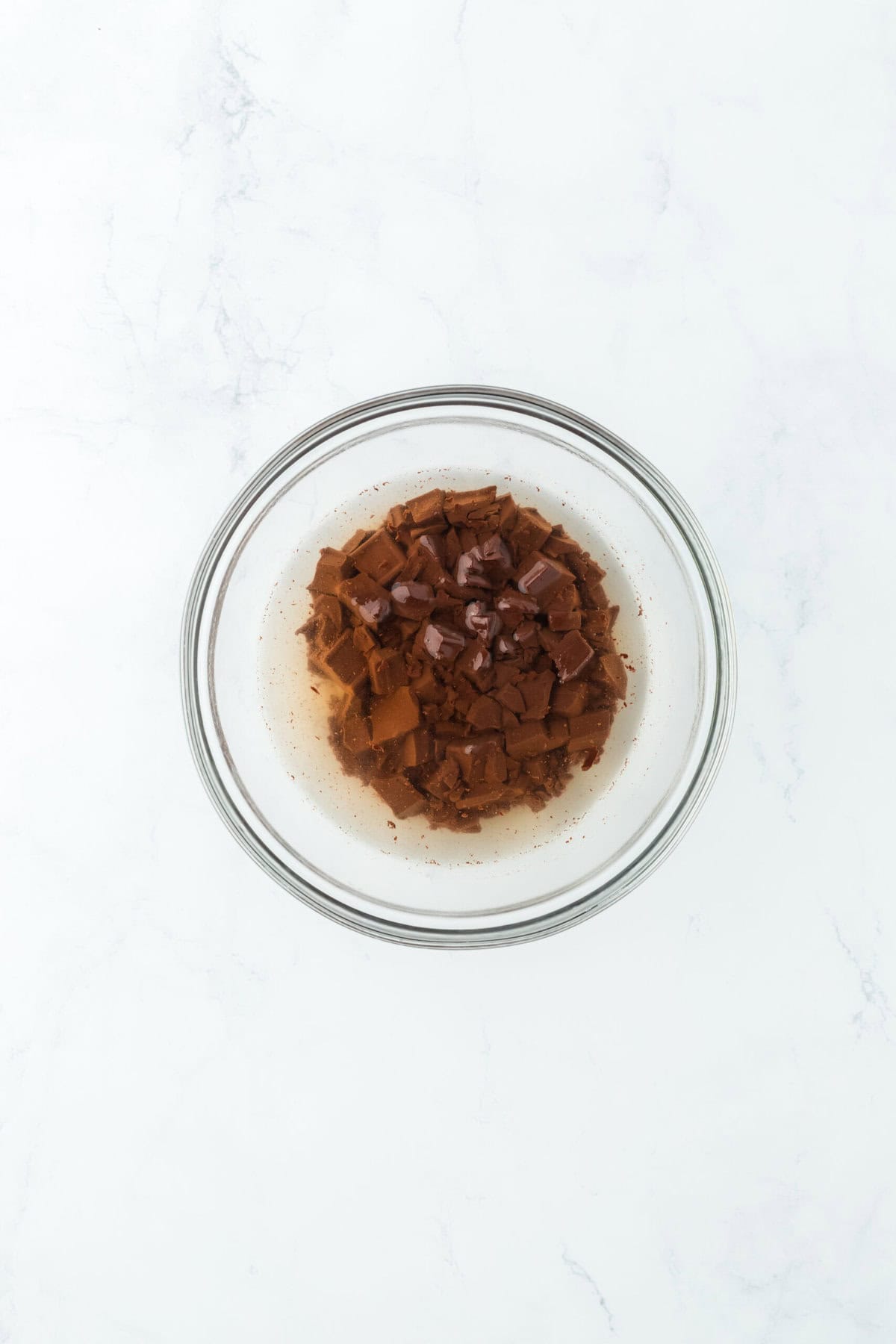 Chopped chocolate and boiling water in glass bowl.