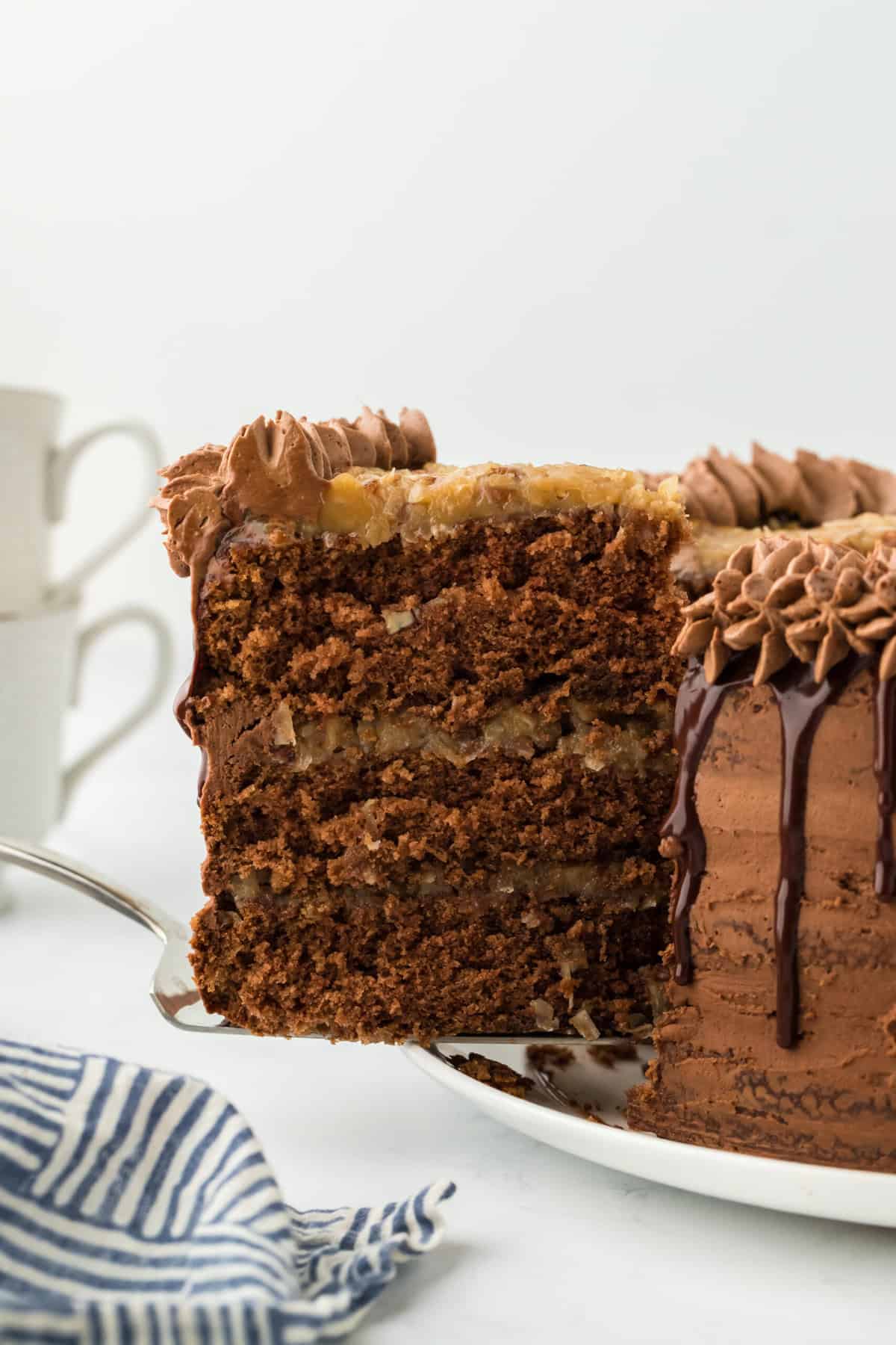 A slice of homemade German chocolate cake being lifted after being cut on white background