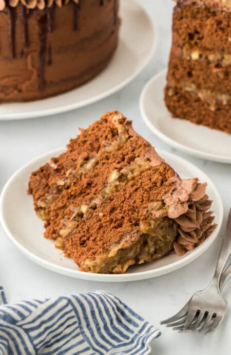 A slice of German cake on a white plate ready to serve