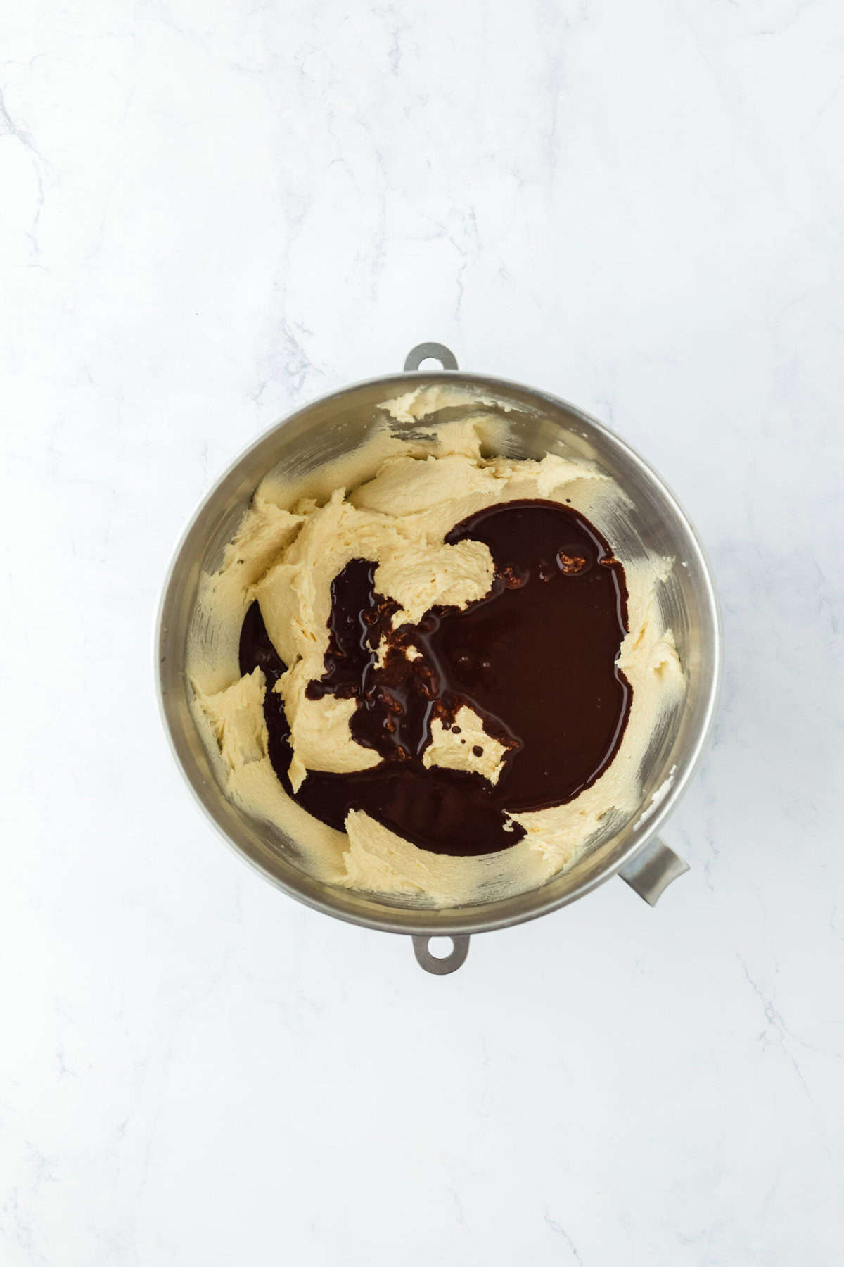 Melted chocolate in cake batter on white countertop.