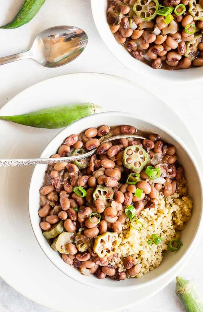 A close up of two bowls with hoppin john ready to eat with spoons