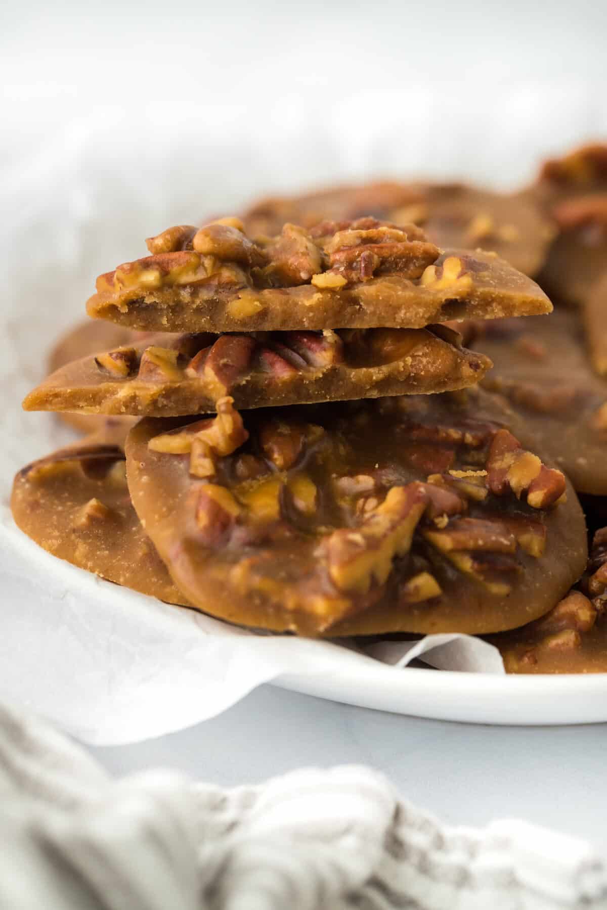 A homemade praline recipe stacked on top of each other on a white plate in white background